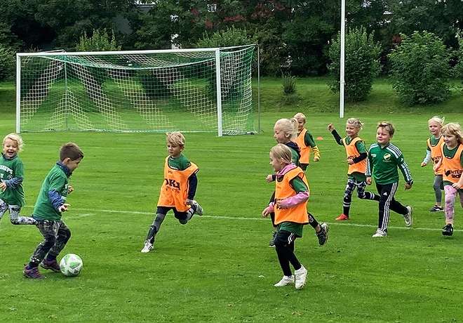 Young children running together on a grass pitch