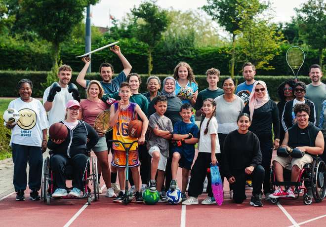 A mixed-age community group including wheelchair users on an athletics track